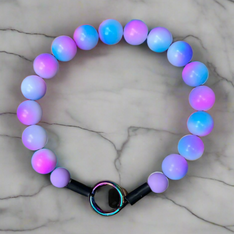 Multicolored beaded bracelet with a black clasp on a marble surface
