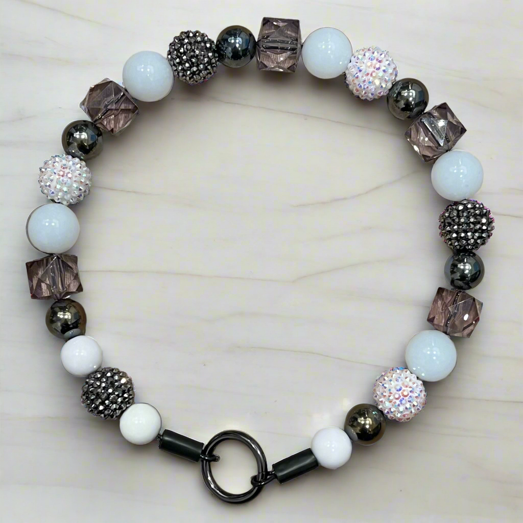 Bracelet with white beads and metallic accents on a light background
