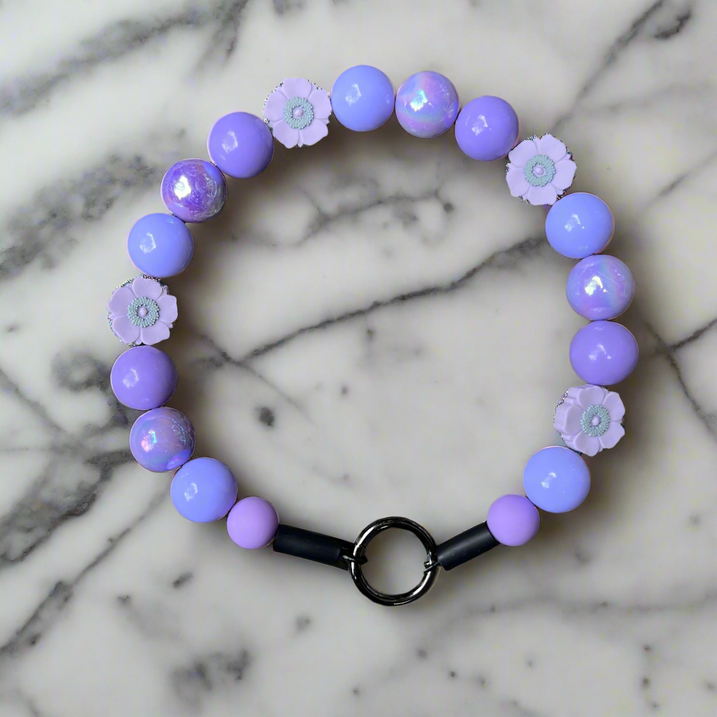 Purple beaded bracelet with floral charms on a marble background