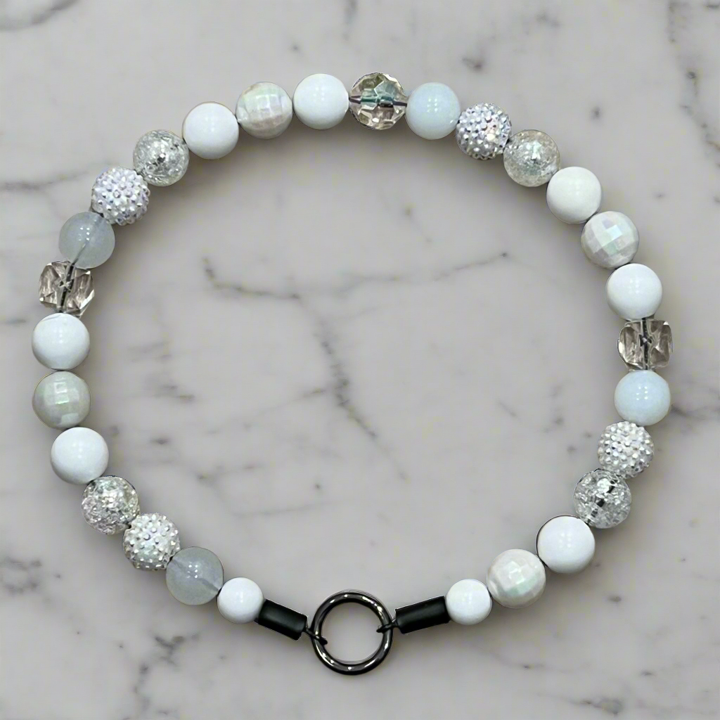 Beaded bracelet with white, gray, and black beads on a marble background
