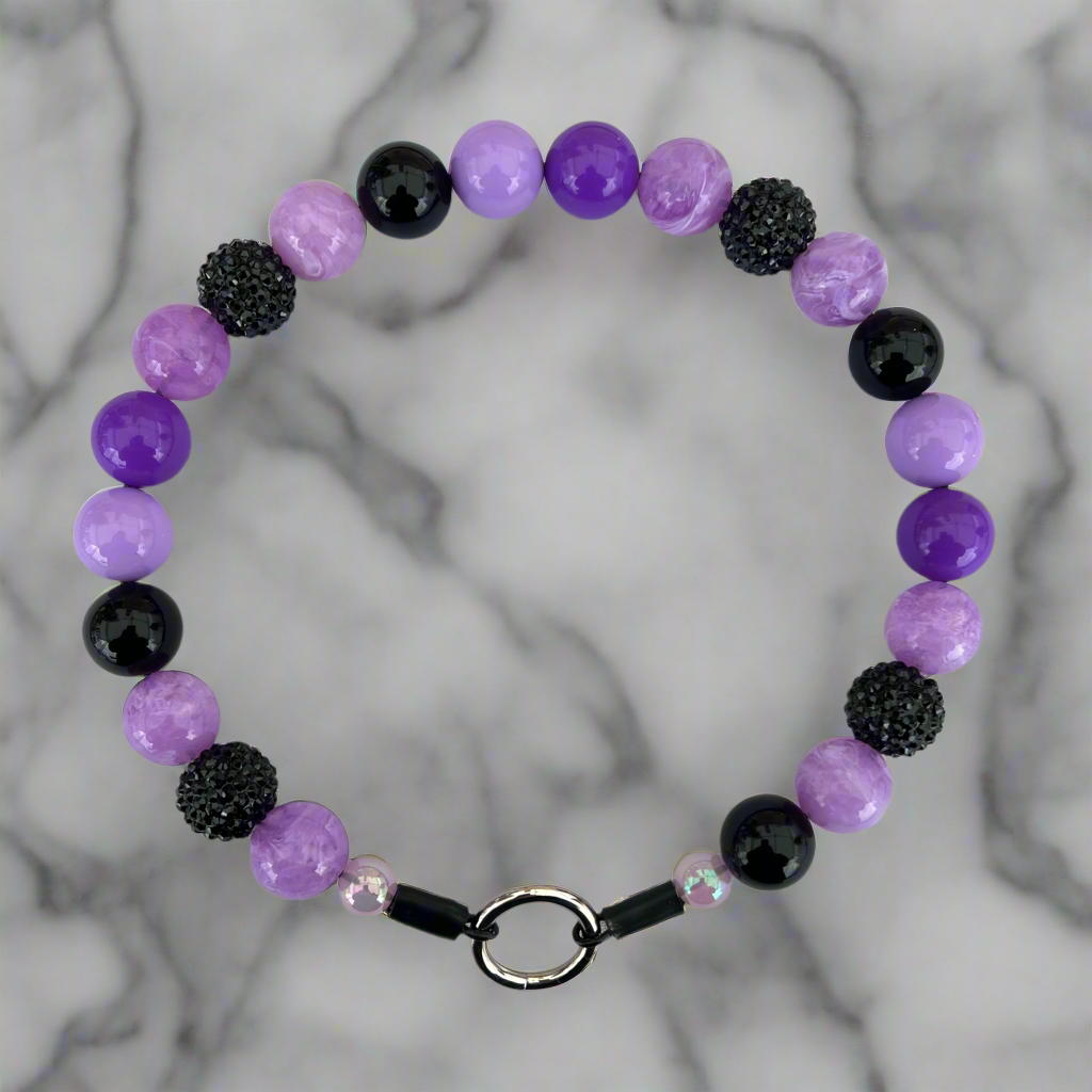 Bracelet with purple, black, and pink beads on a marble background