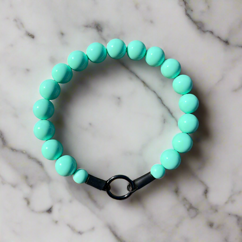 Turquoise beaded bracelet with a black clasp on a marble background