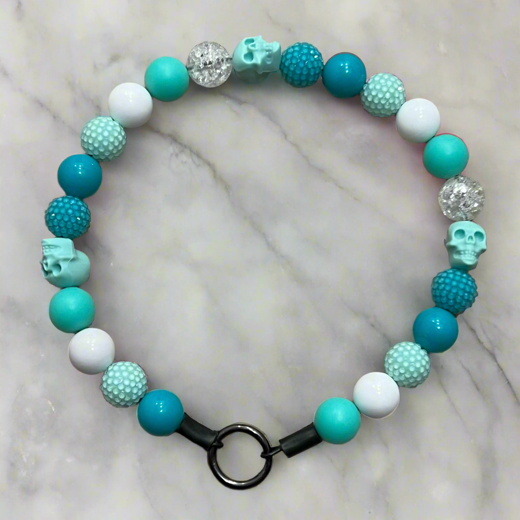 Beaded bracelet with turquoise, white, and teal beads on a marble background