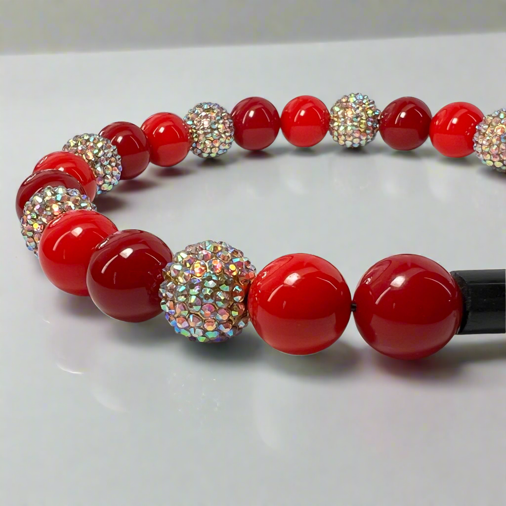 Necklace with red beads and rhinestone accents on a white background
