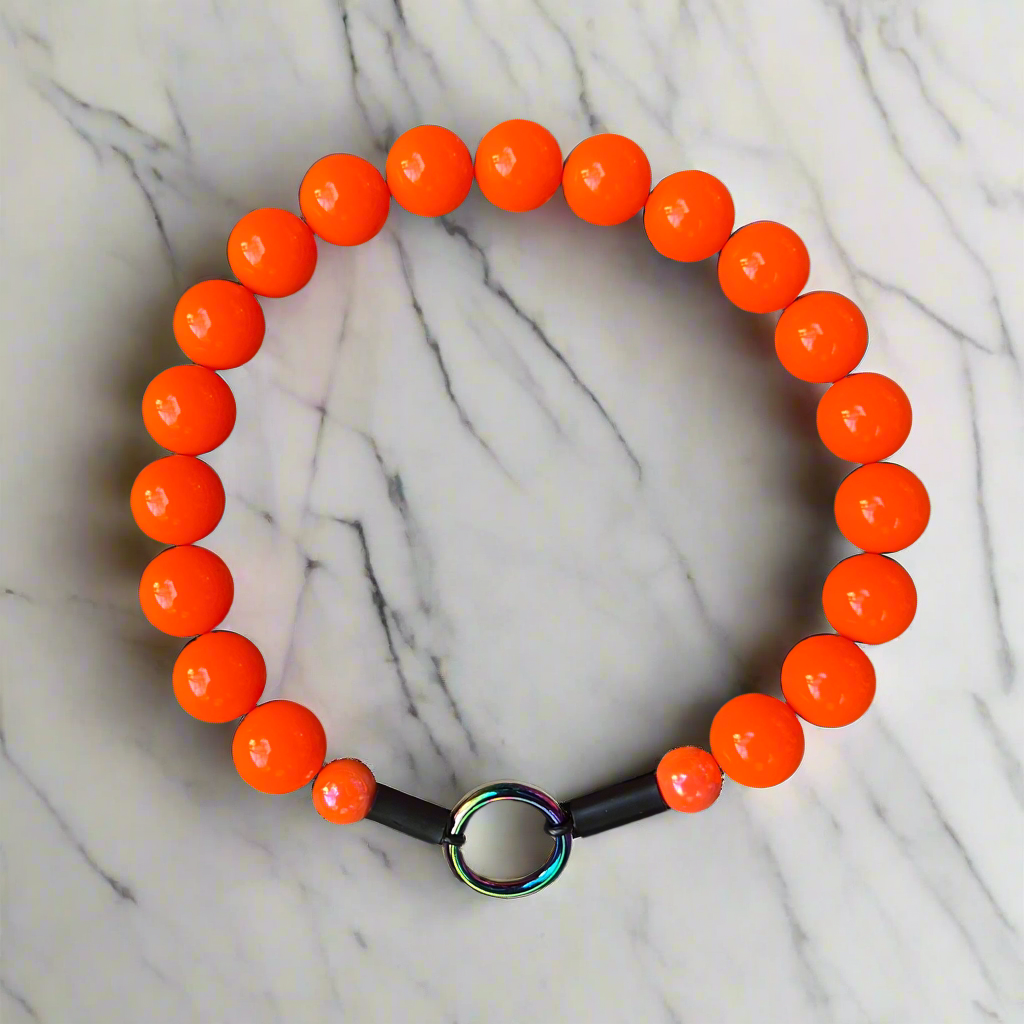Orange beaded bracelet with a black band on a marble background