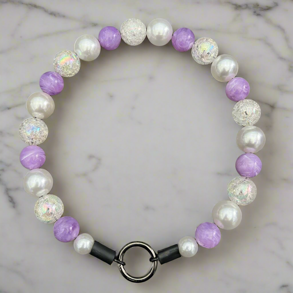 Beaded bracelet with purple, white, and silver beads on a marble background