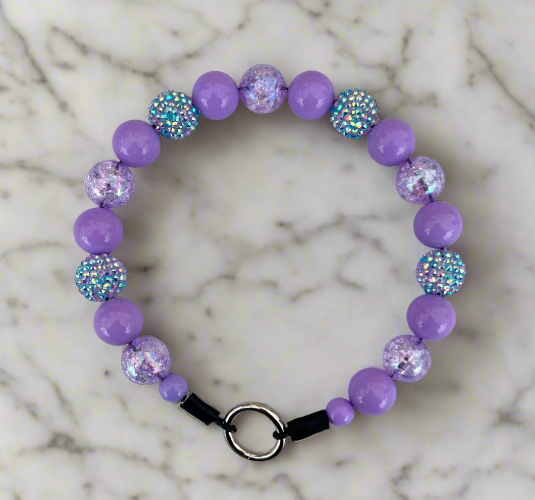 Purple beaded bracelet with glittery accents on a marble background