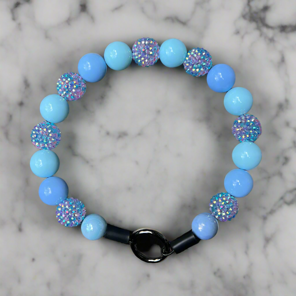 Bracelet with blue beads and black clasp on a marble background