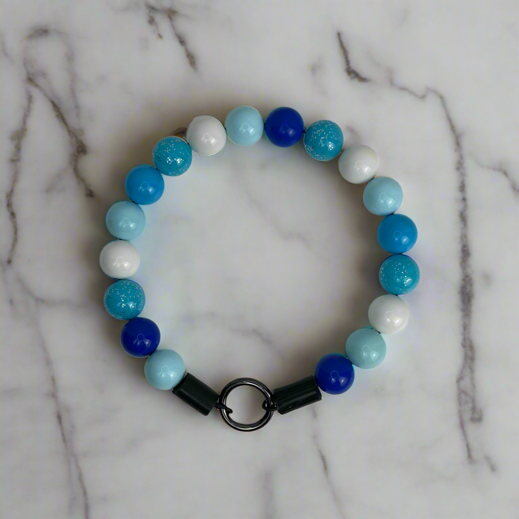 Beaded bracelet with blue, white, and turquoise beads on a marble surface