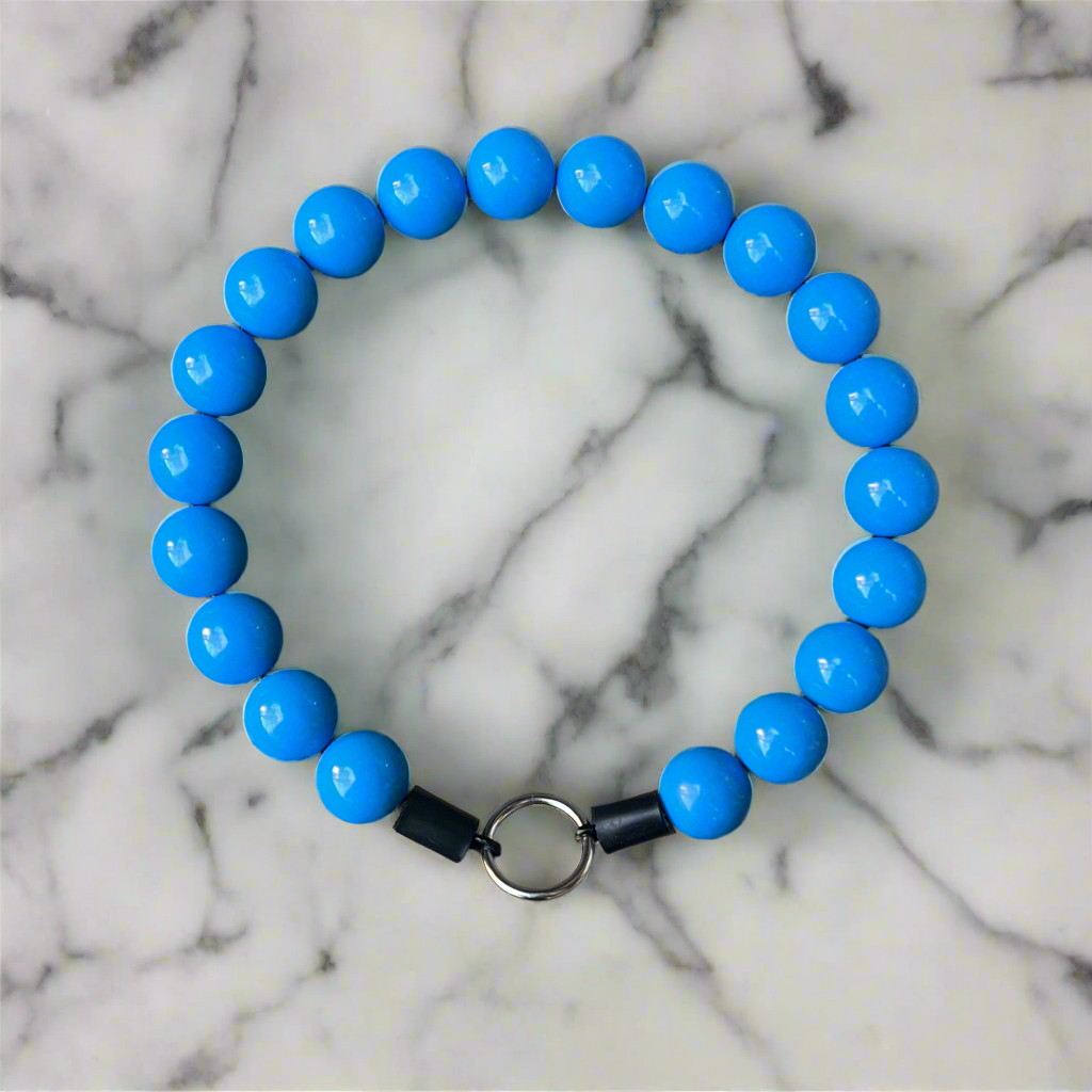 Blue beaded bracelet with a black and silver clasp on a marble background