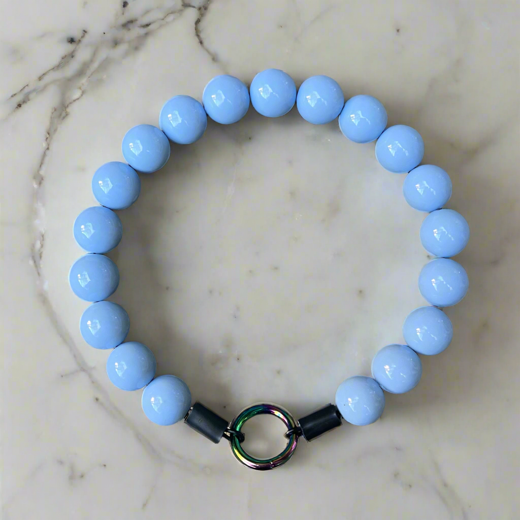Blue beaded bracelet with a metal clasp on a marble surface