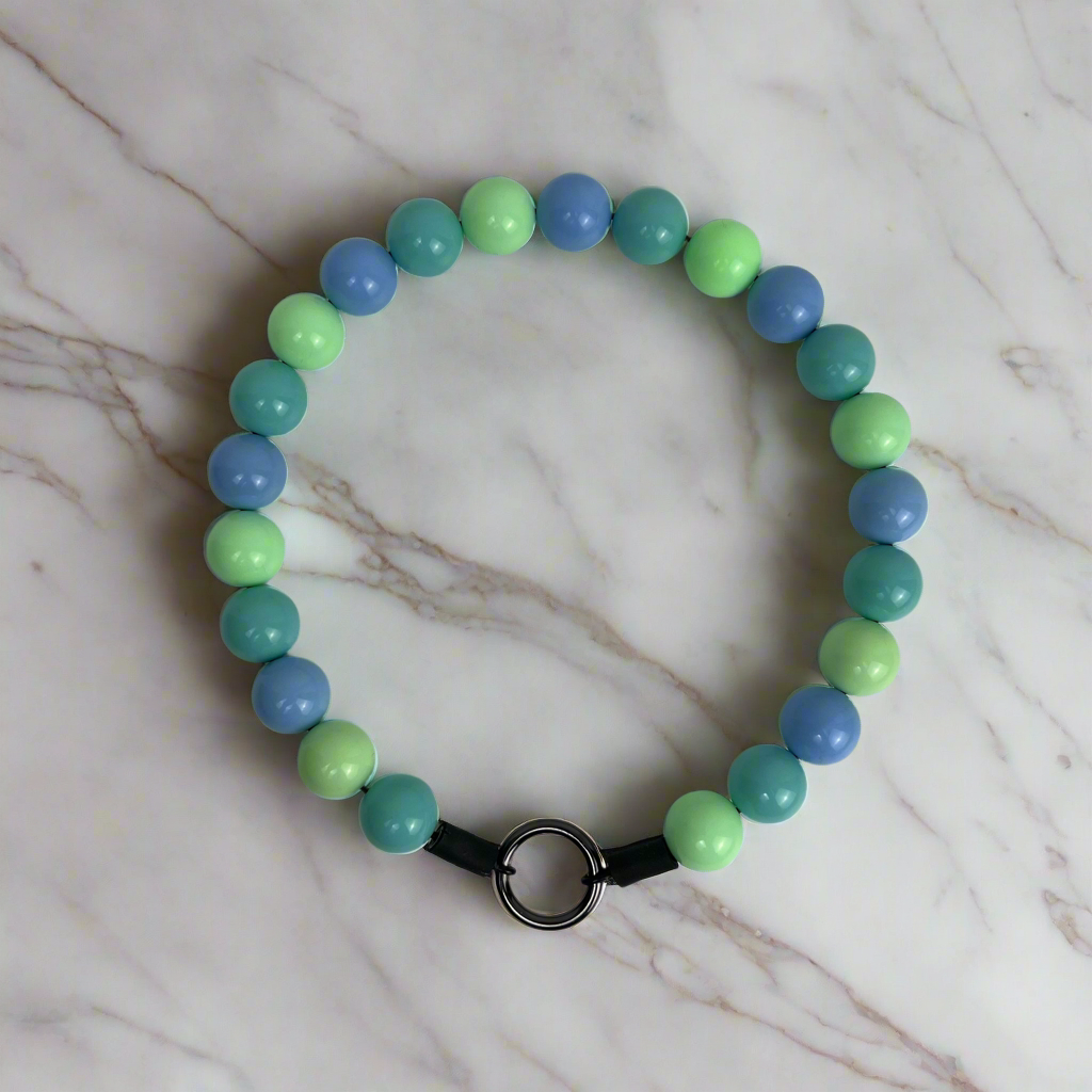 Beaded bracelet with blue, green, and teal beads on a marble surface