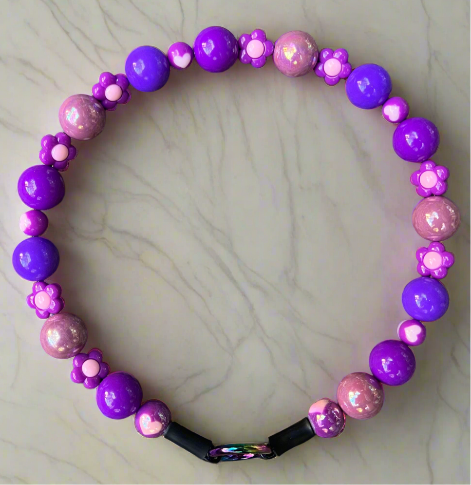 Purple and pink beaded necklace on a marble surface