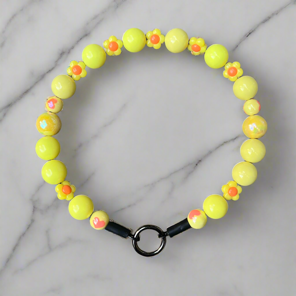 Neon yellow beaded bracelet with black clasp on a marble background