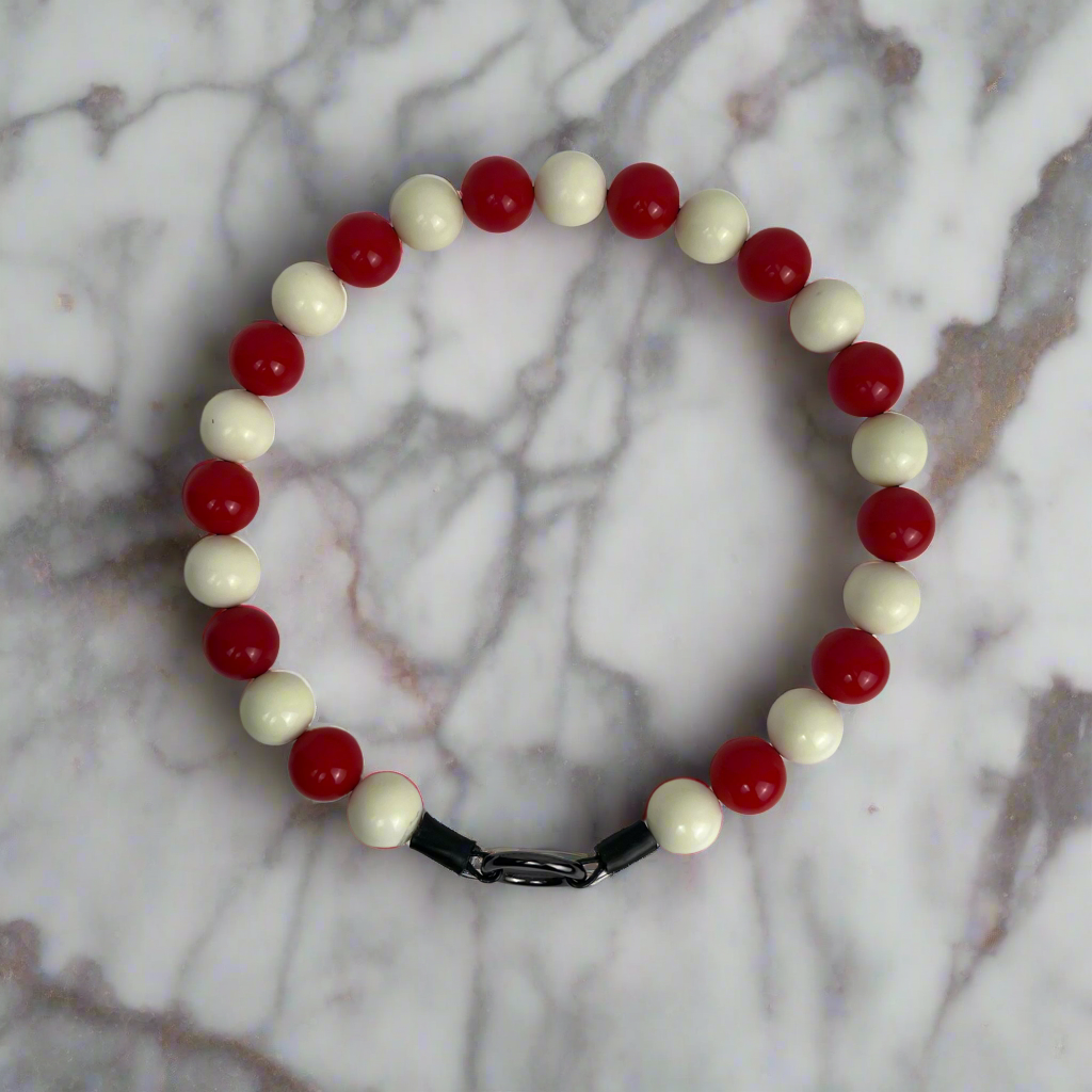 Bracelet with red and white beads on a marble background
