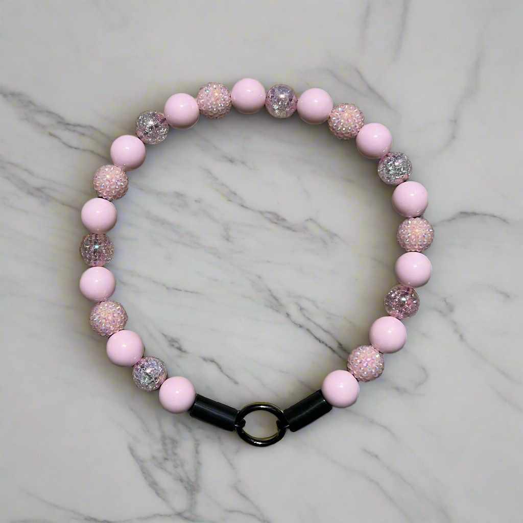 Pink beaded bracelet with glittery accents on a marble surface