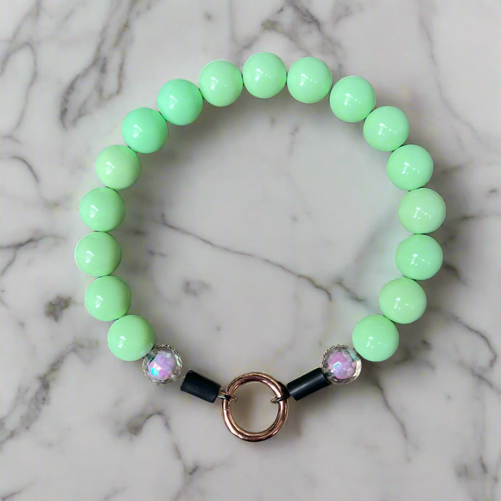 Green beaded bracelet with decorative elements on a marble background