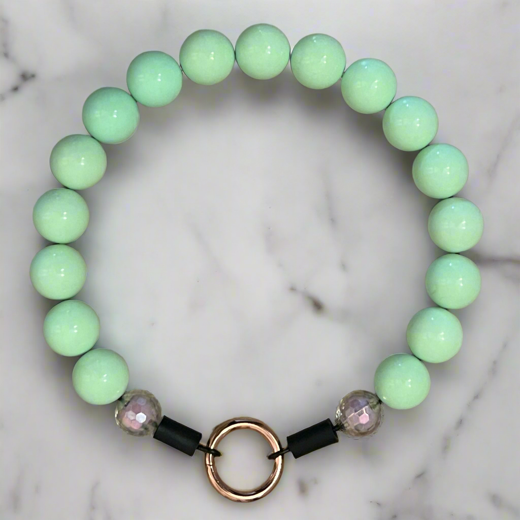 Mint green beaded bracelet with black and rose gold accents on a marble background