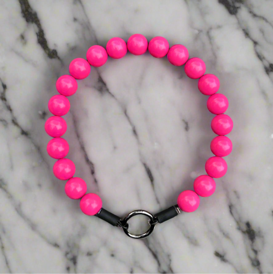 Pink beaded bracelet with a black clasp on a marble background