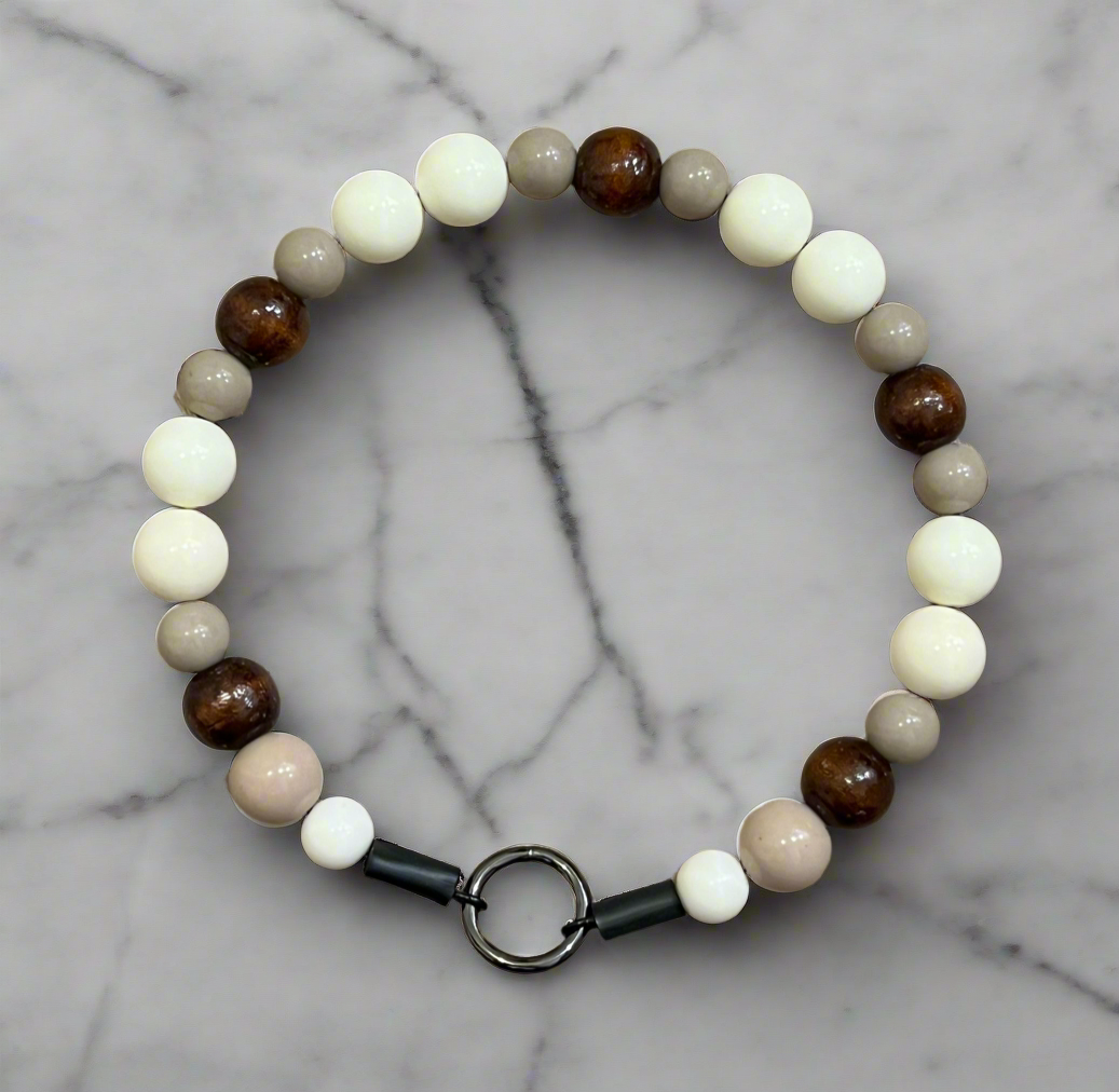 Beaded bracelet with brown, beige, and white beads on a marble background