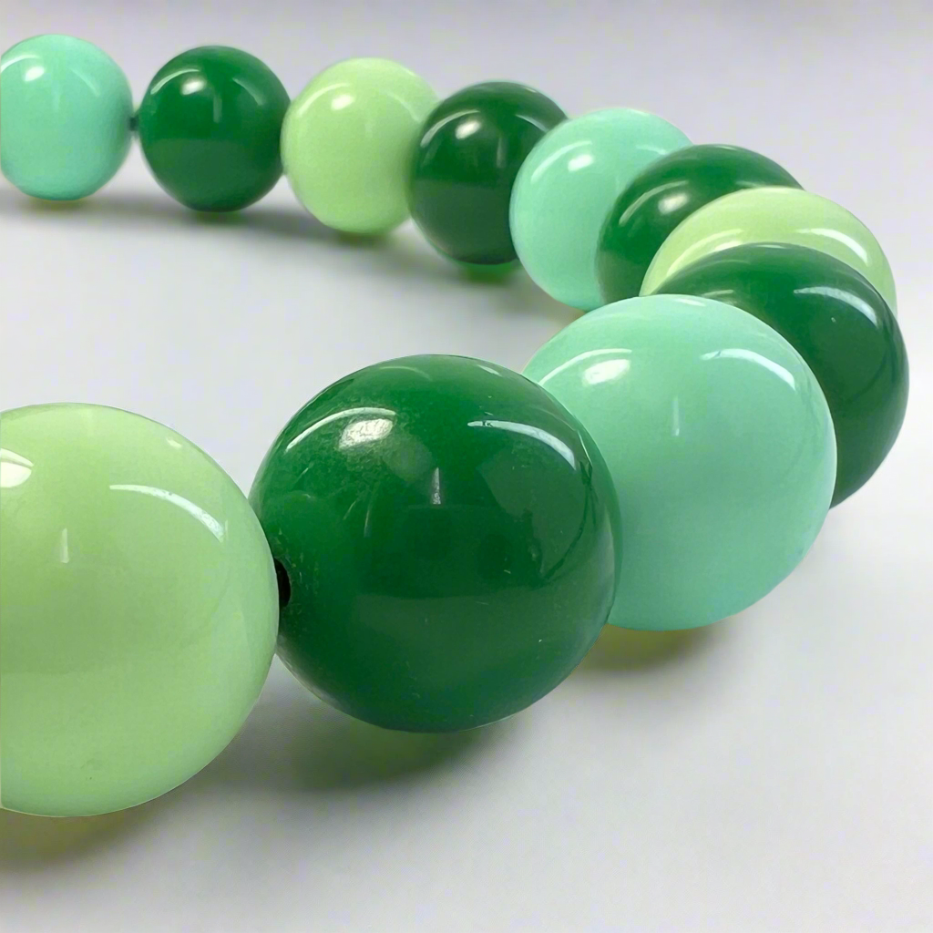 Green and light green beaded bracelet on a white background