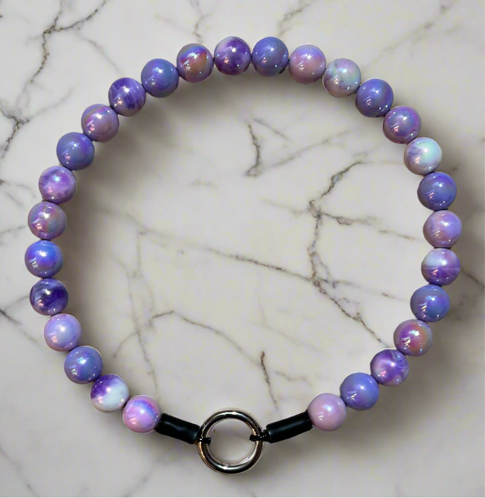 Beaded bracelet with purple and pink stones on a marble surface
