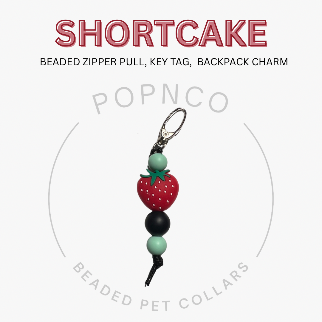 Beaded zipper pull, key tag, or backpack charm with strawberry design on a white background, featuring the brand 'Popnco'.