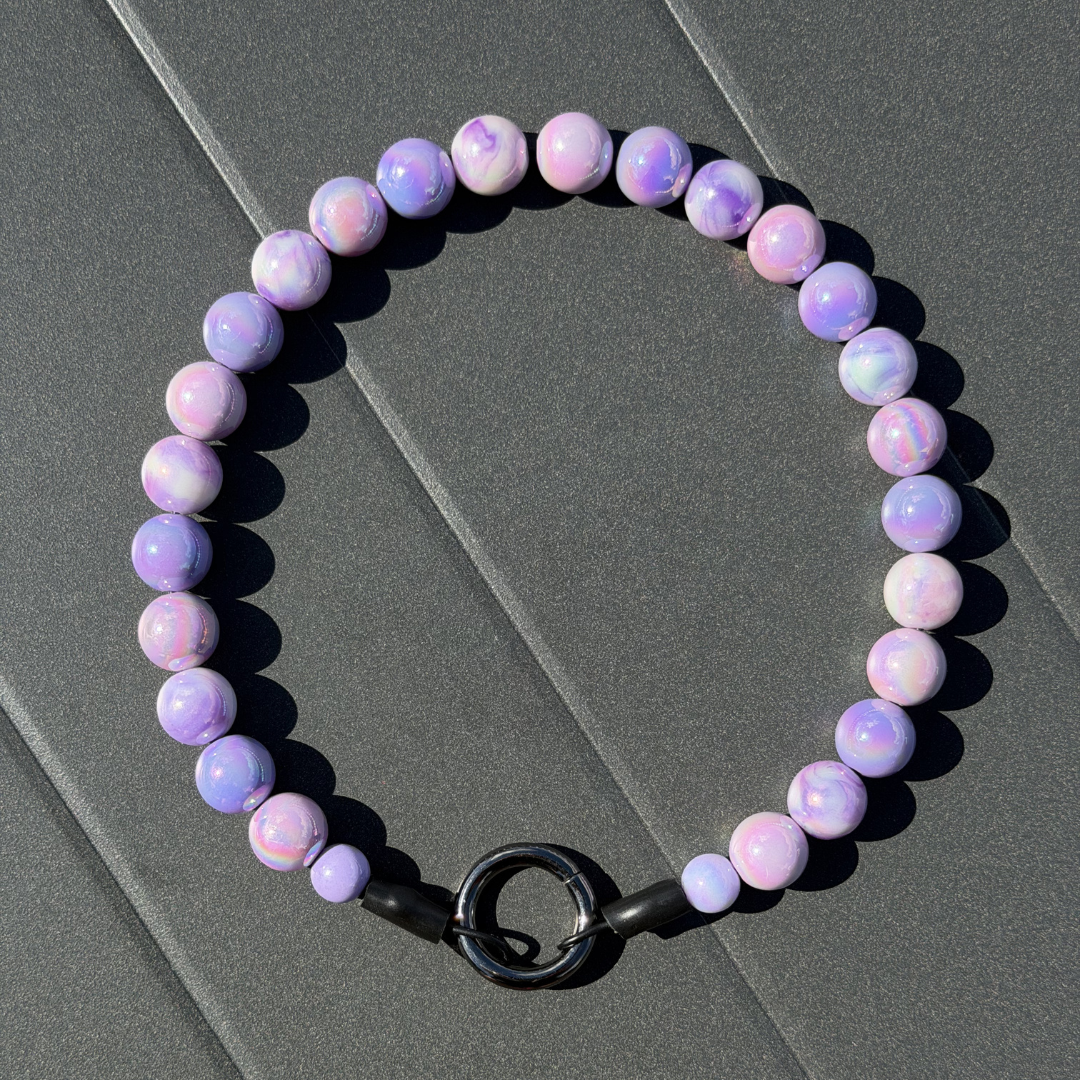 Purple beaded dog collar with a black clasp on a gray surface from POPNCO