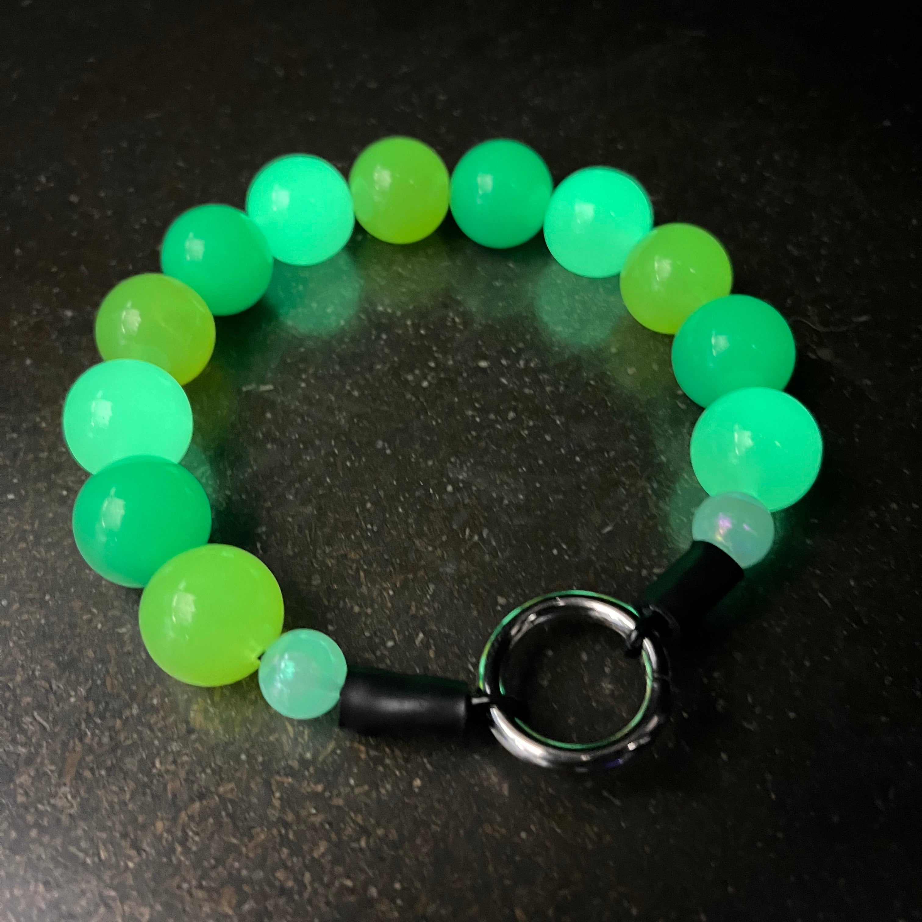Green beaded pet collar that glows in the dark from POPNCO on a dark surface