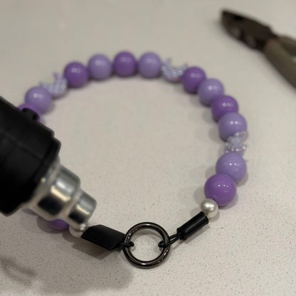 Purple beaded collar with a black clasp on a white surface, with a ruler for scale. Behind the Scenes of shrink wrapping a slip om style beaded pet collar from POPNCO Beaded Pet Collars in BC Canada. 