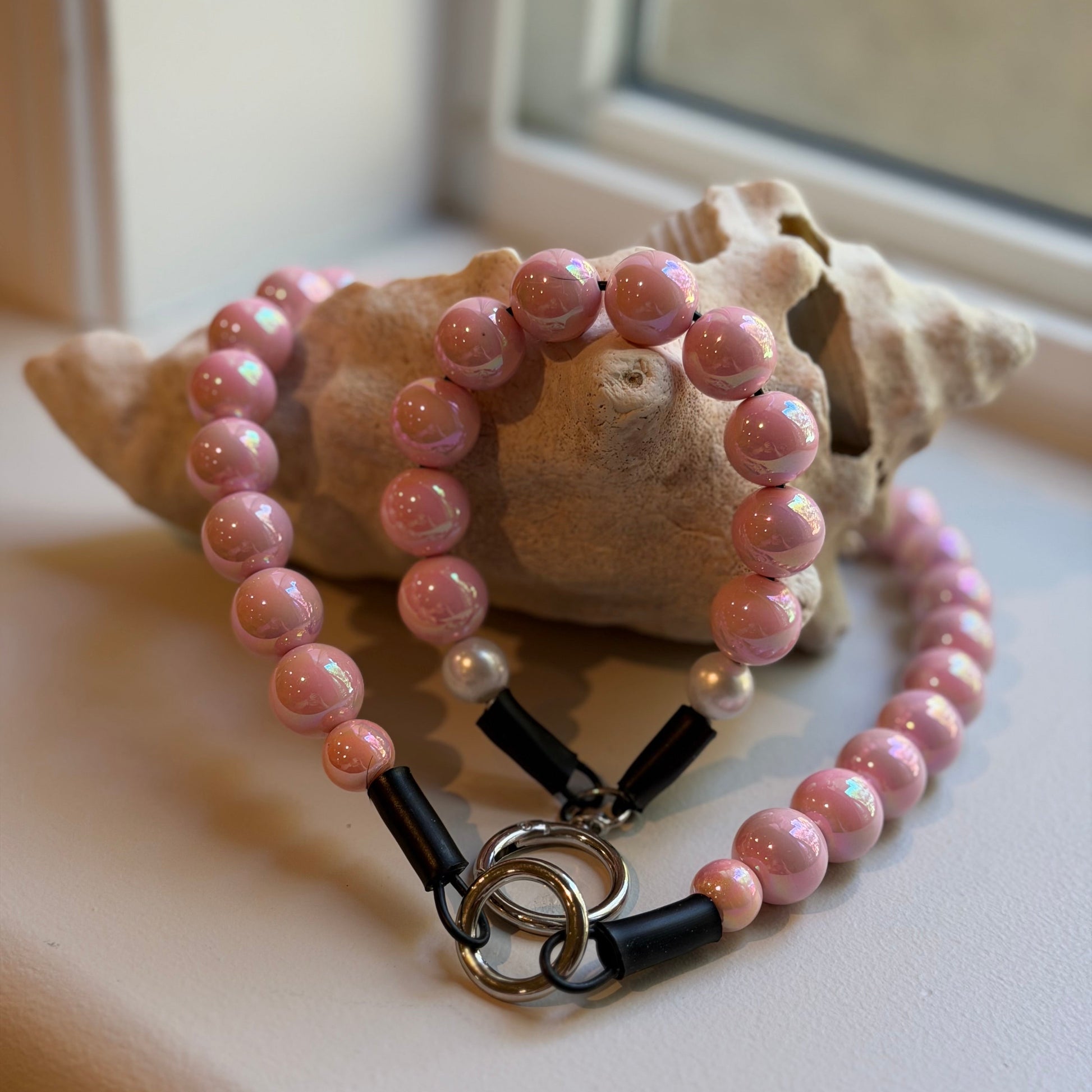 Pink beaded necklace with black accents on a shell