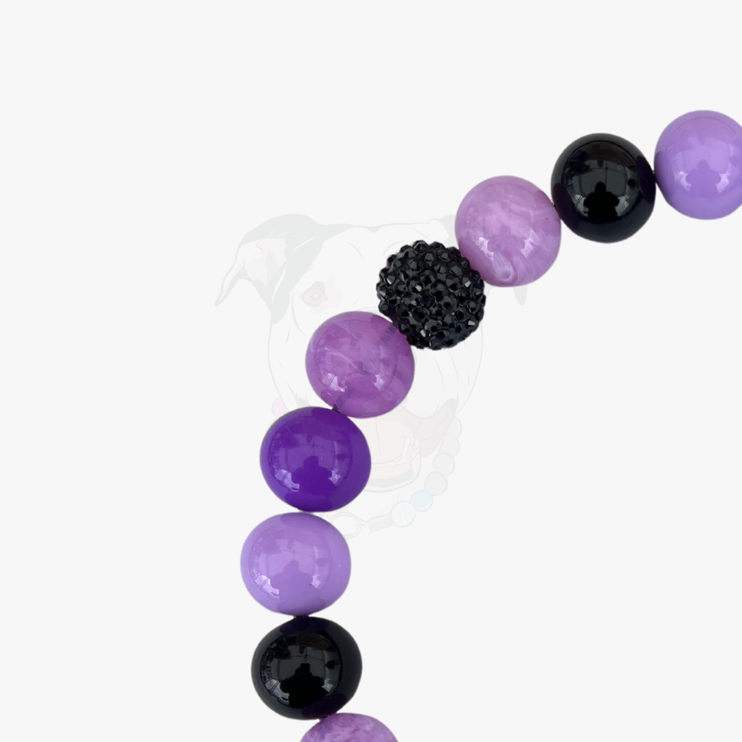 Beaded bracelet with purple and black beads on a white background
