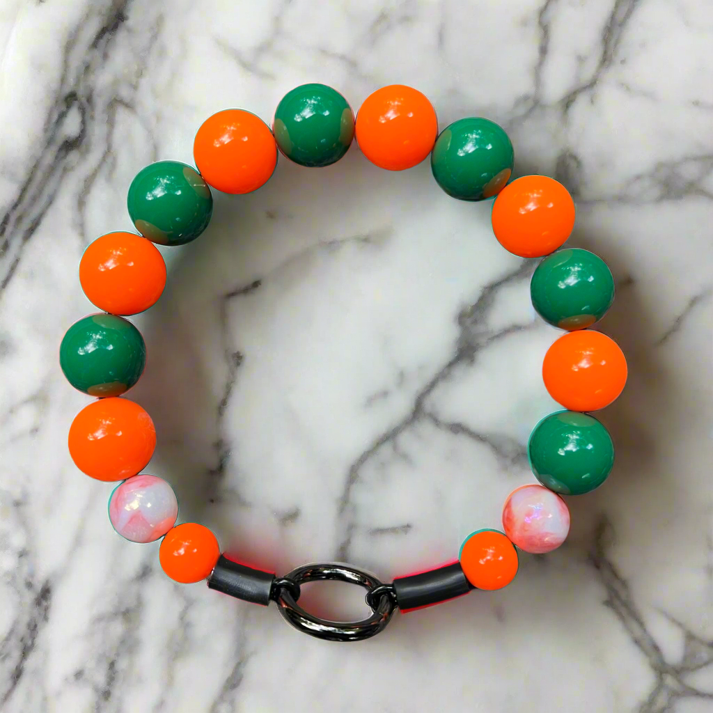 Bracelet with green and orange beads on a marble background