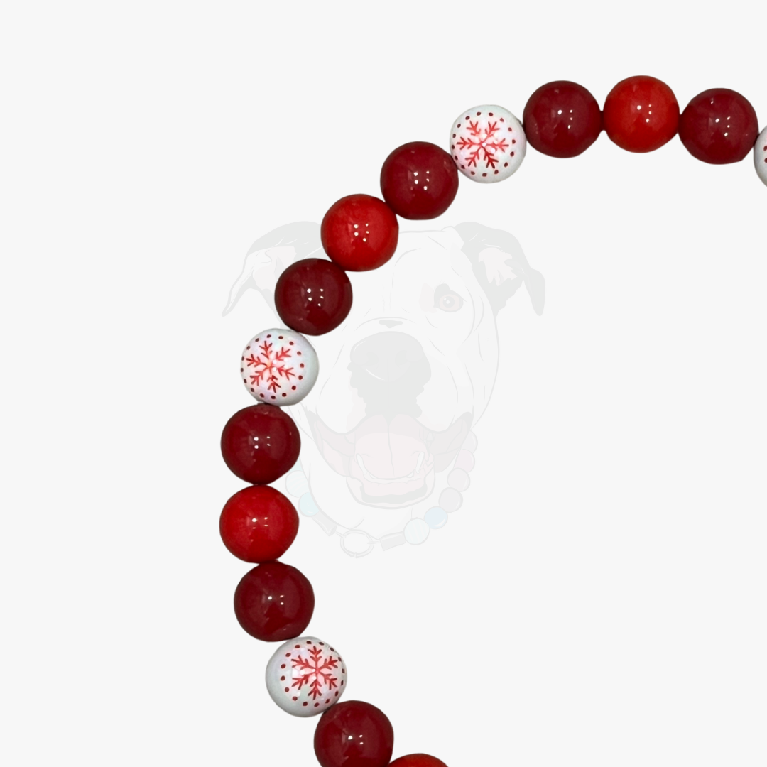Beaded necklace with red and white snowflake pattern beads on a white background