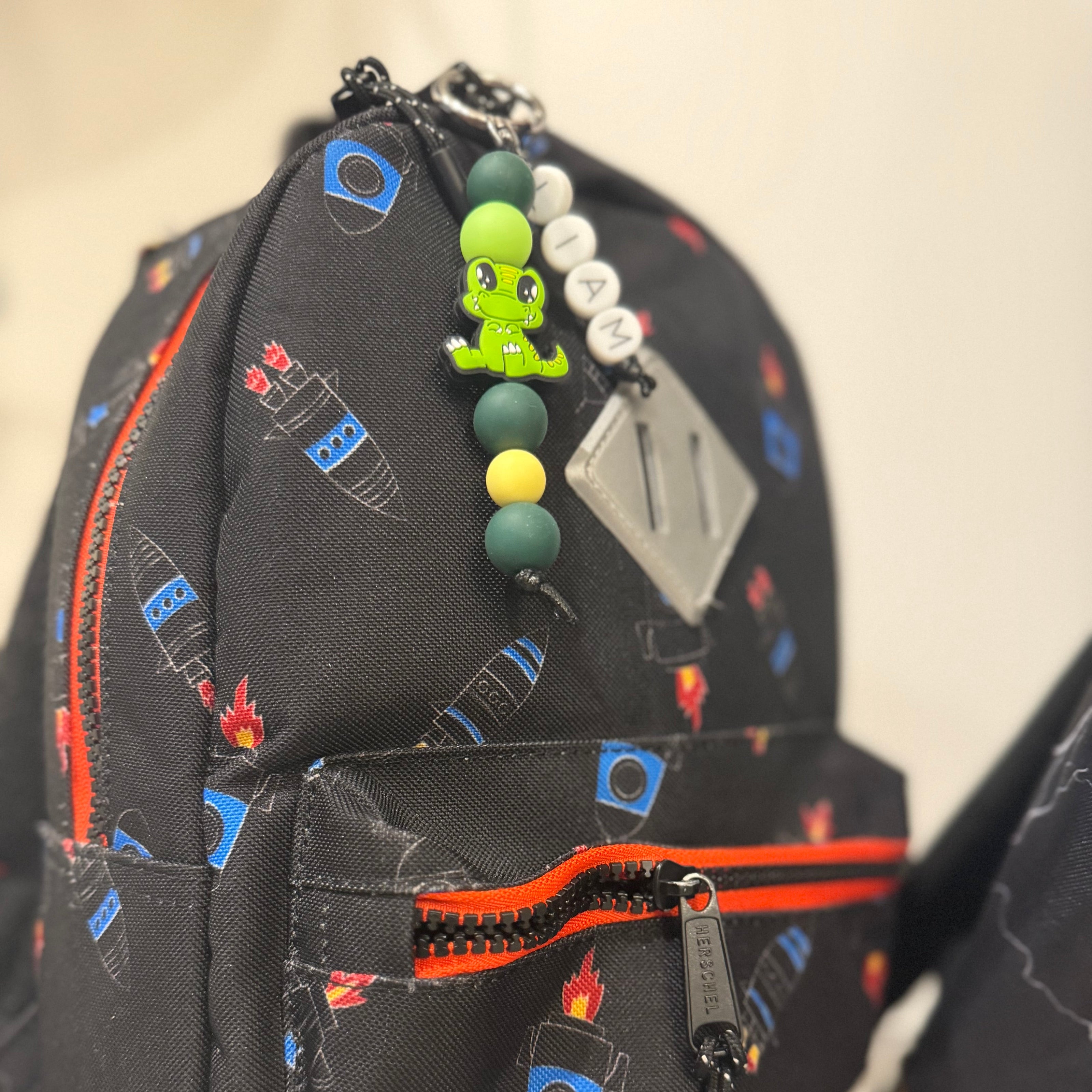 Black backpack with colorful patterns and keychains on a white background POPNCO