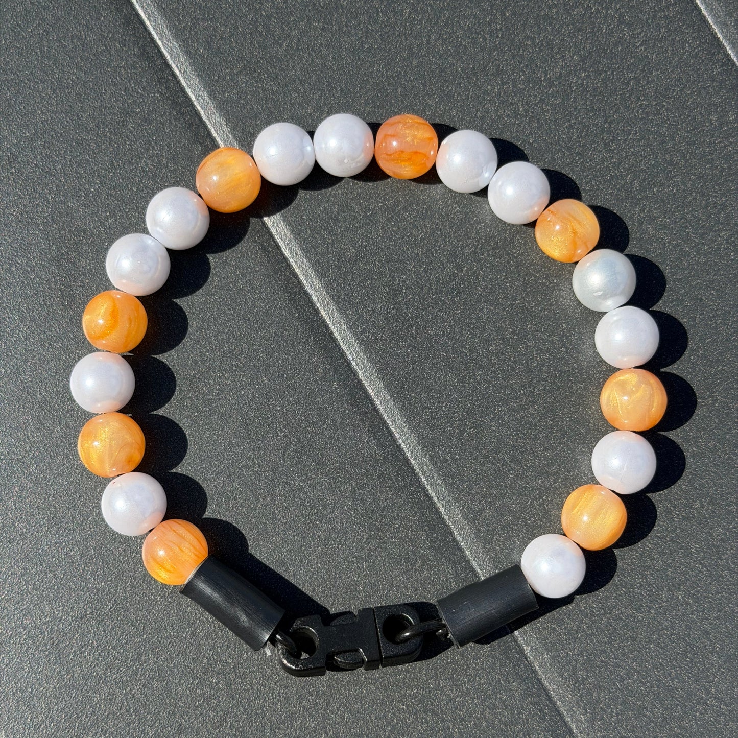 Galaxy Collection Orange and pearl 12mm beaded pet collar on aircraft grade stainless steel wire laying flat on a grey black background