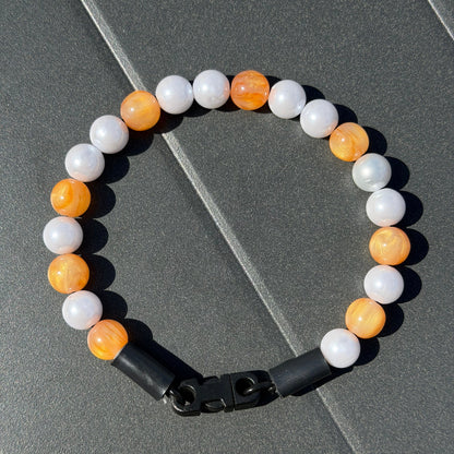 Galaxy Collection Orange and pearl 12mm beaded pet collar on aircraft grade stainless steel wire laying flat on a grey black background