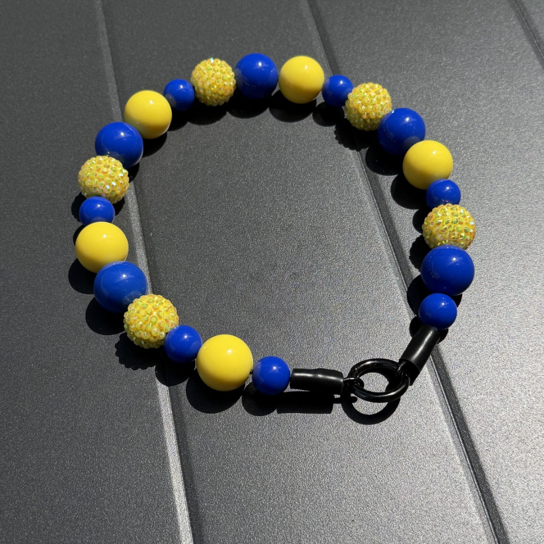 POPNCO Homer beaded pet collar. from the Biggie Smalls collection, featuring alternating Yellow and Blue acrylic beads on aircraft grade stainless steel wire. POPNCO beaded pet collar Homer from the Biggie Smalls collection, featuring alternating Yellow and Blue acrylic beads on aircraft grade stainless steel wire laying flat on grey table