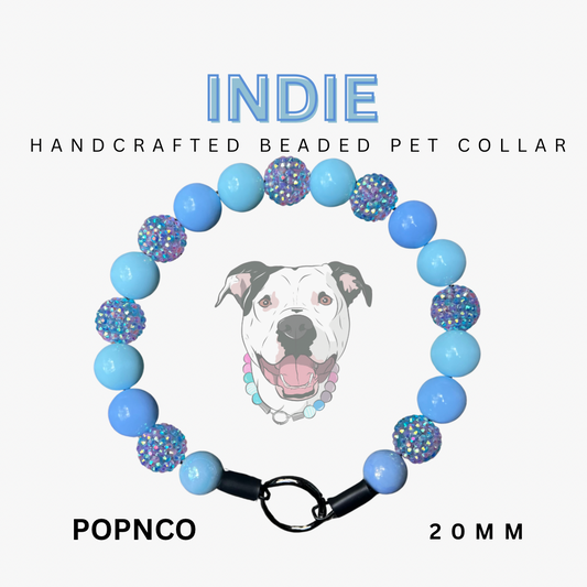 Handcrafted beaded pet collar with blue and multicolored beads, featuring a dog illustration and brand name on a white background.