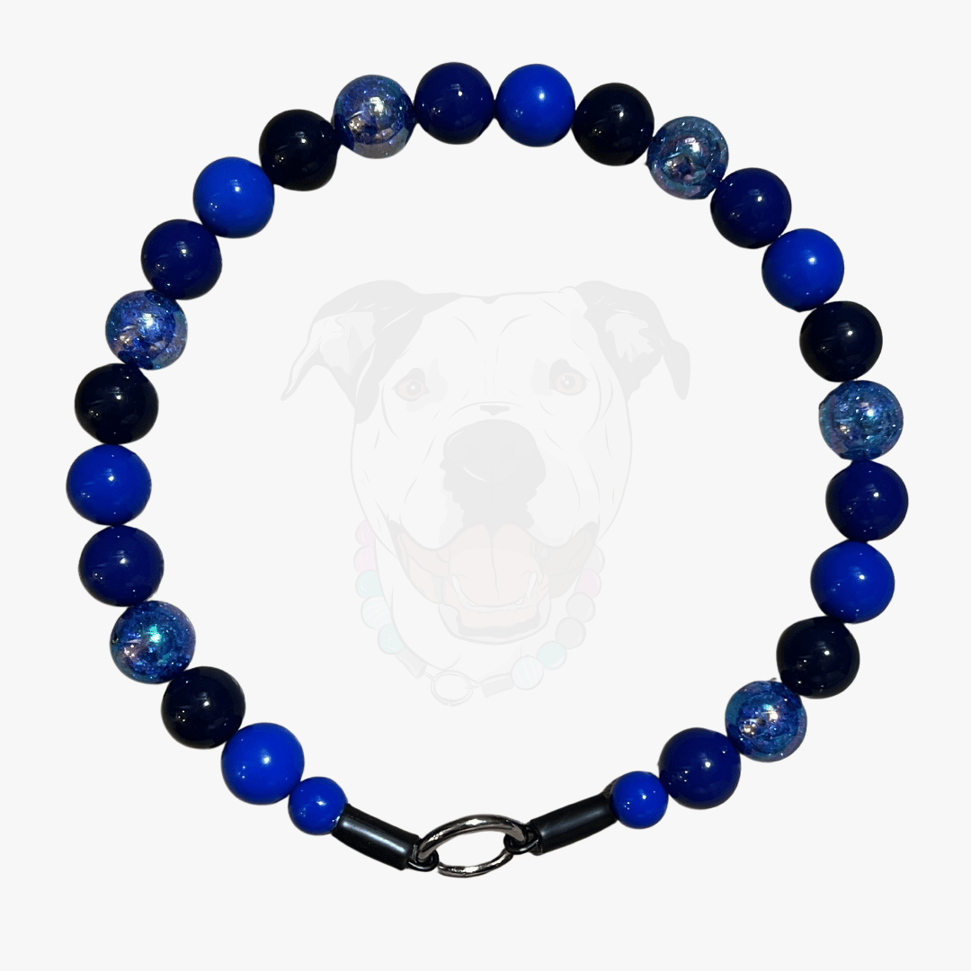 The indigo blue beaded pet collar featuring alternating royal blue, dark blue and navy blue solid beads mixed with blue crackle beads in 20mm on  aircraft grade stainless steel wire laying flat on a white background. 