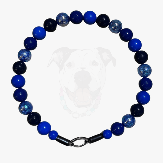 The indigo blue beaded pet collar featuring alternating royal blue, dark blue and navy blue solid beads mixed with blue crackle beads in 20mm on  aircraft grade stainless steel wire laying flat on a white background. 