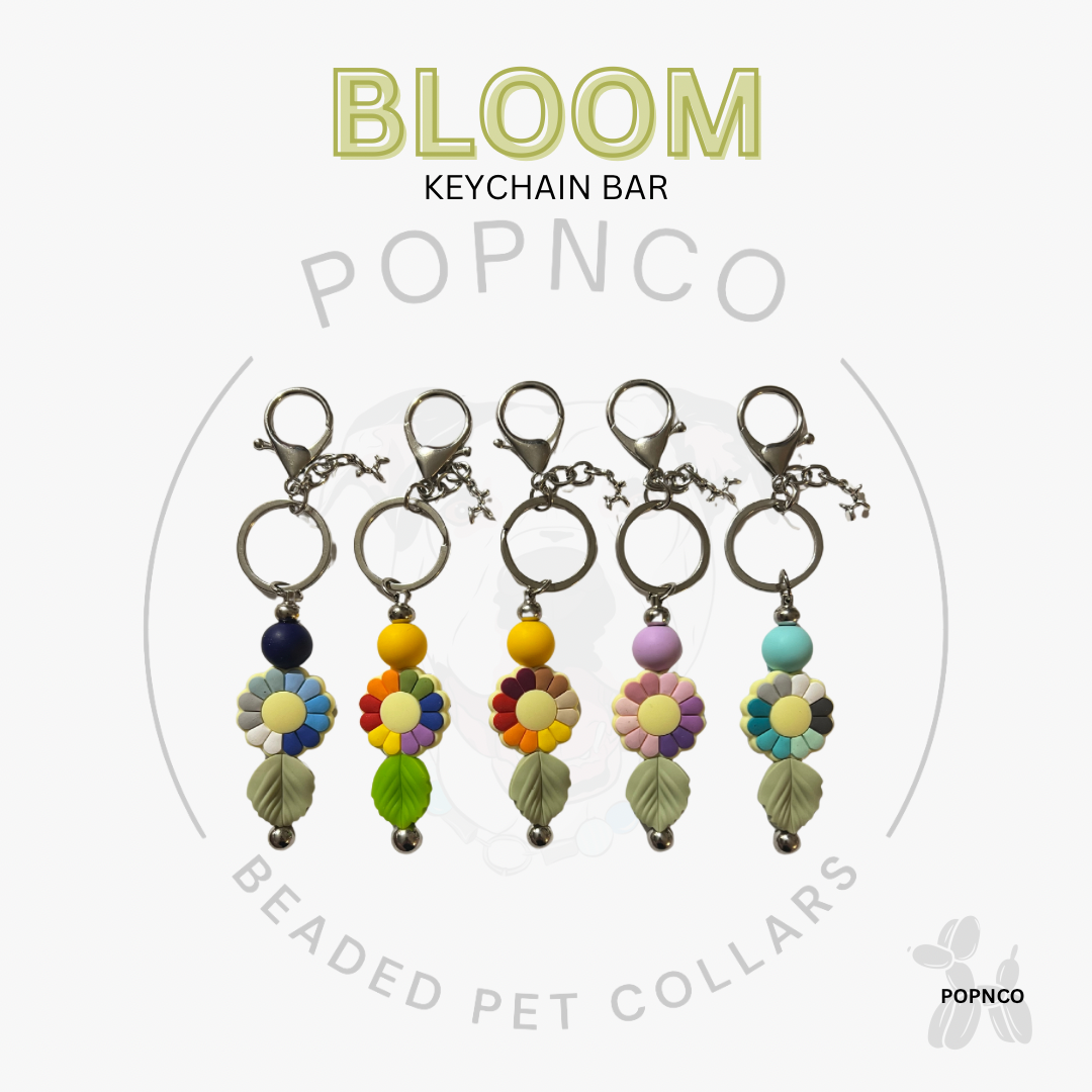 Set of colorful flower-shaped keychain bars with 'BLOOM' text and 'POPNCO' branding on a white background.