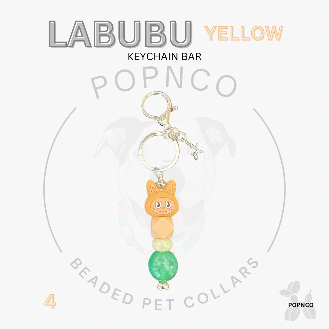 Yellow keychain bar with cat-shaped charm and green beads on a white background, featuring LABUBU branding.