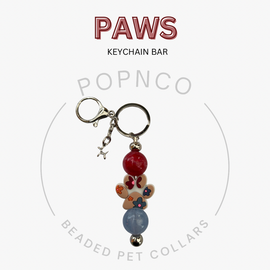 Keychain bar with paw-shaped charm and beads on a white background, featuring 'PAWS' and 'POPNCO' text.