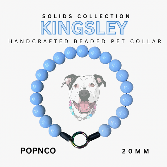 Handcrafted beaded pet collar with blue beads and a dog illustration, labeled 'Kingsley' from the Solids Collection.