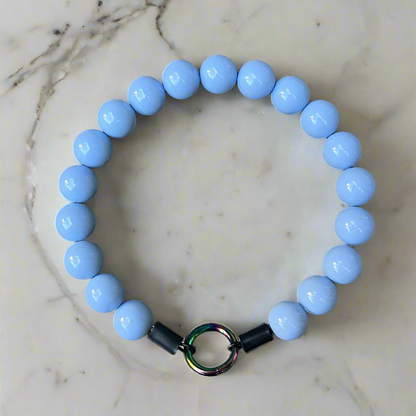 Blue beaded bracelet with a metal clasp on a marble surface