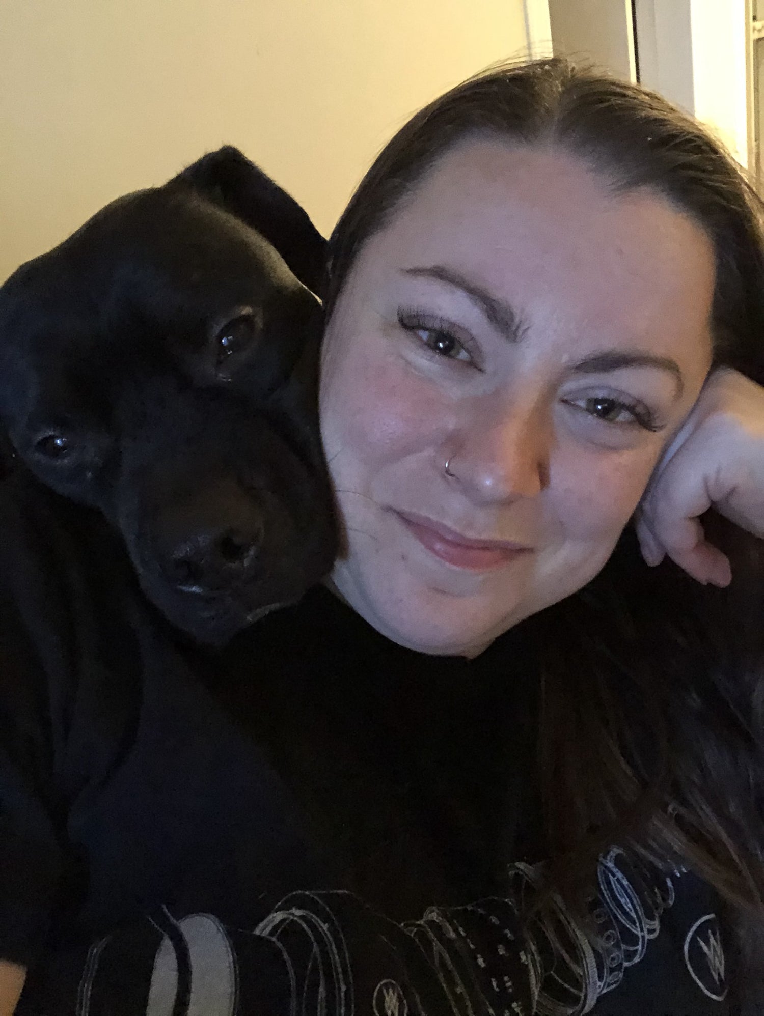 Woman with a black dog on a light-colored wall background