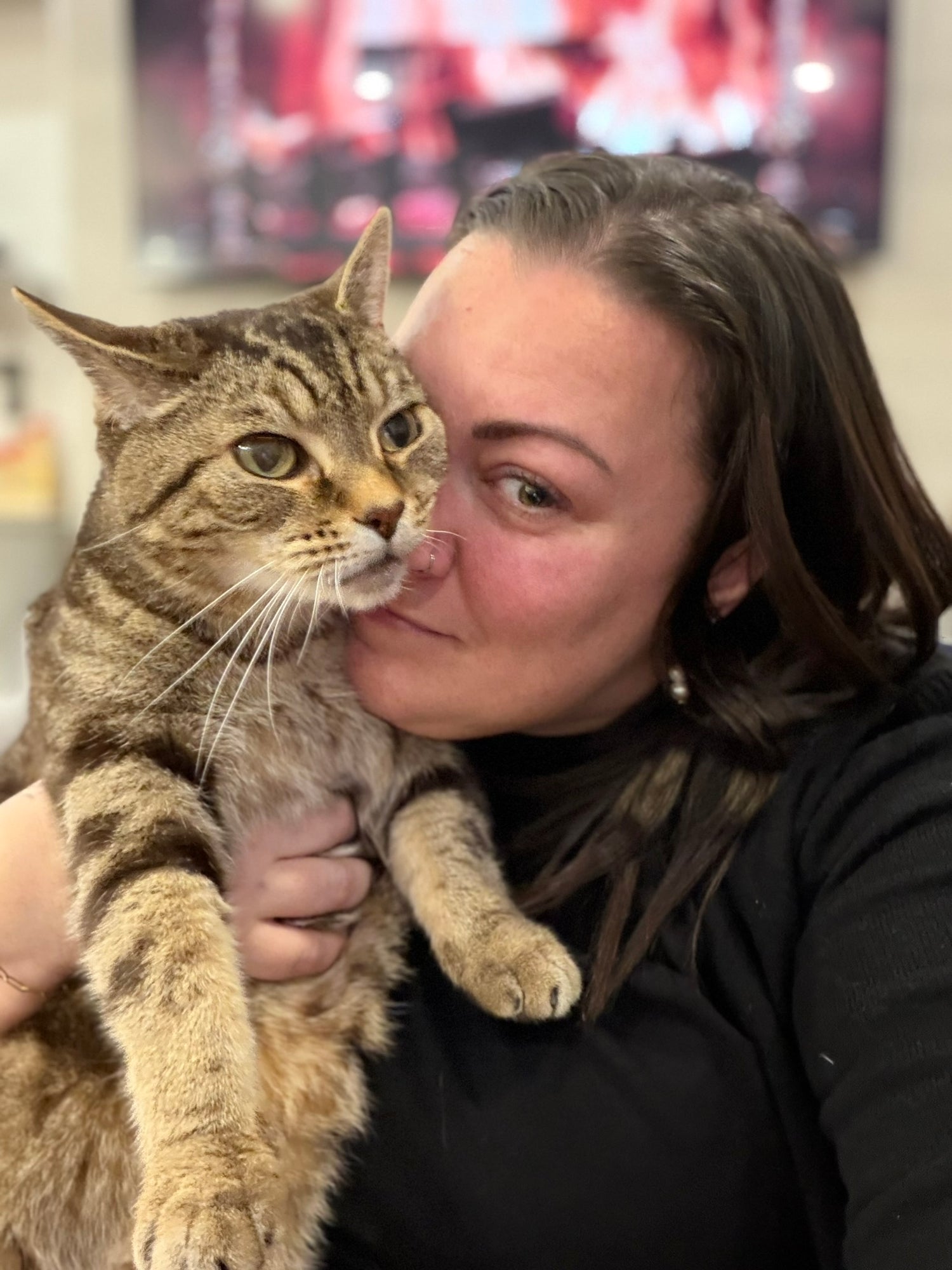 Woman holding a cat in an indoor setting with blurred background