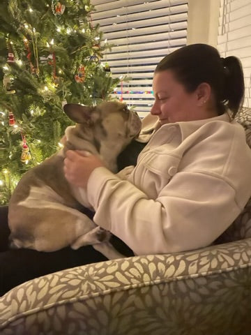 Woman holding a dog in front of a Christmas tree