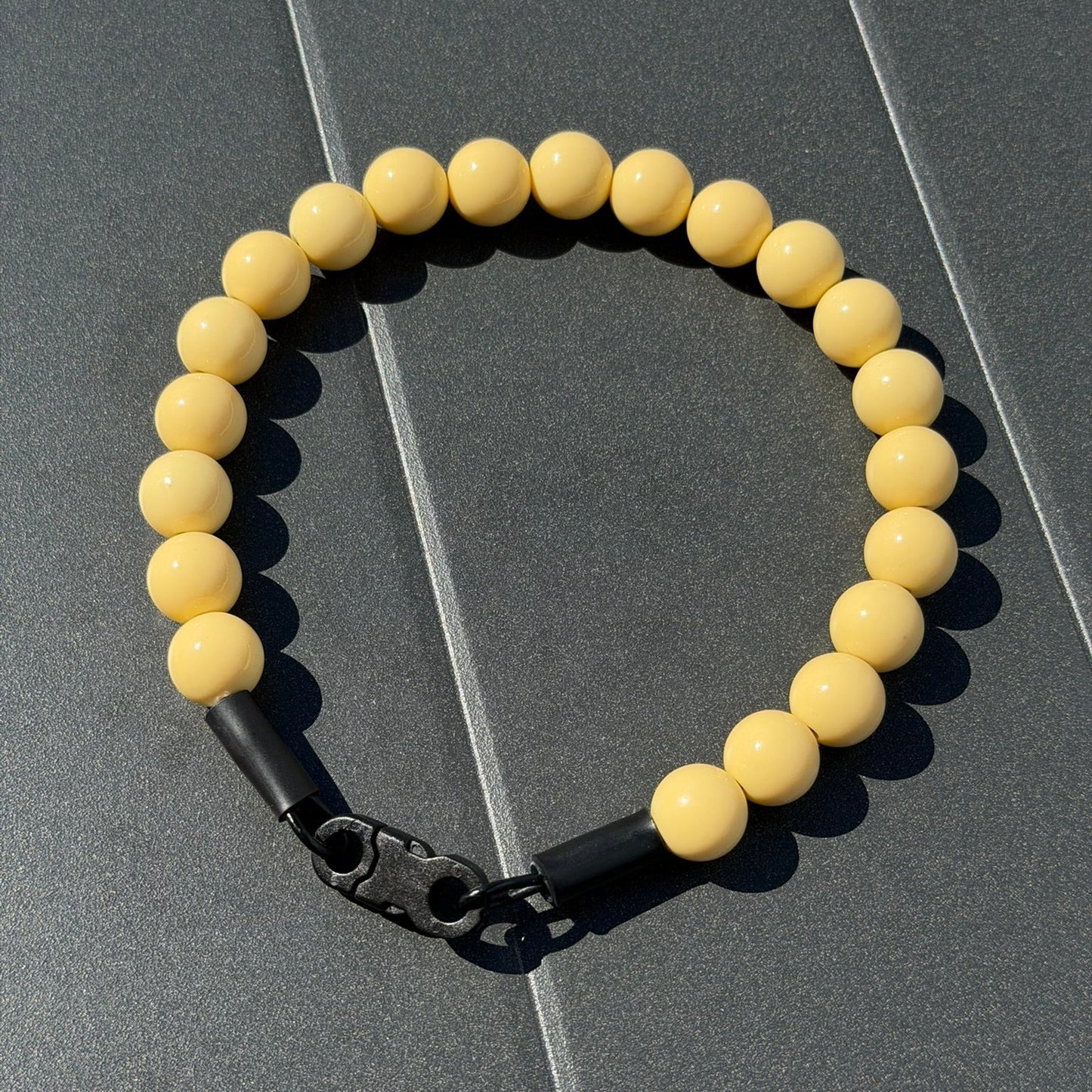 Yellow beaded collar with a black metal clasp on a gray surface